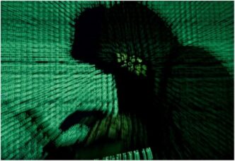 Hooded man holds laptop computer as cyber code is projected on him in this illustration picture Reuters